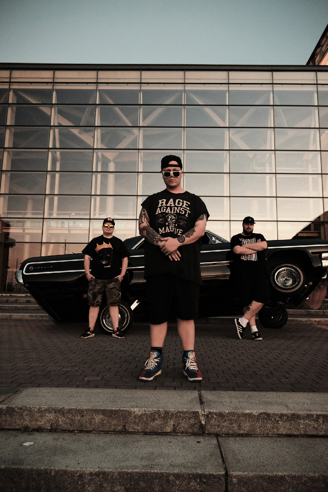 Lyömättömät bändi seisoo amerikanraudan edessä.