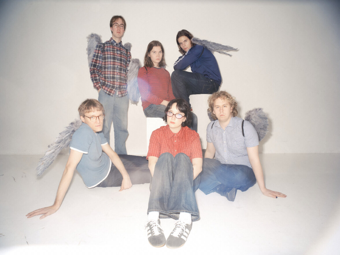 Yhyteen jäsenet kuvattu valokuvastudiossa hopeiset siivet selässään