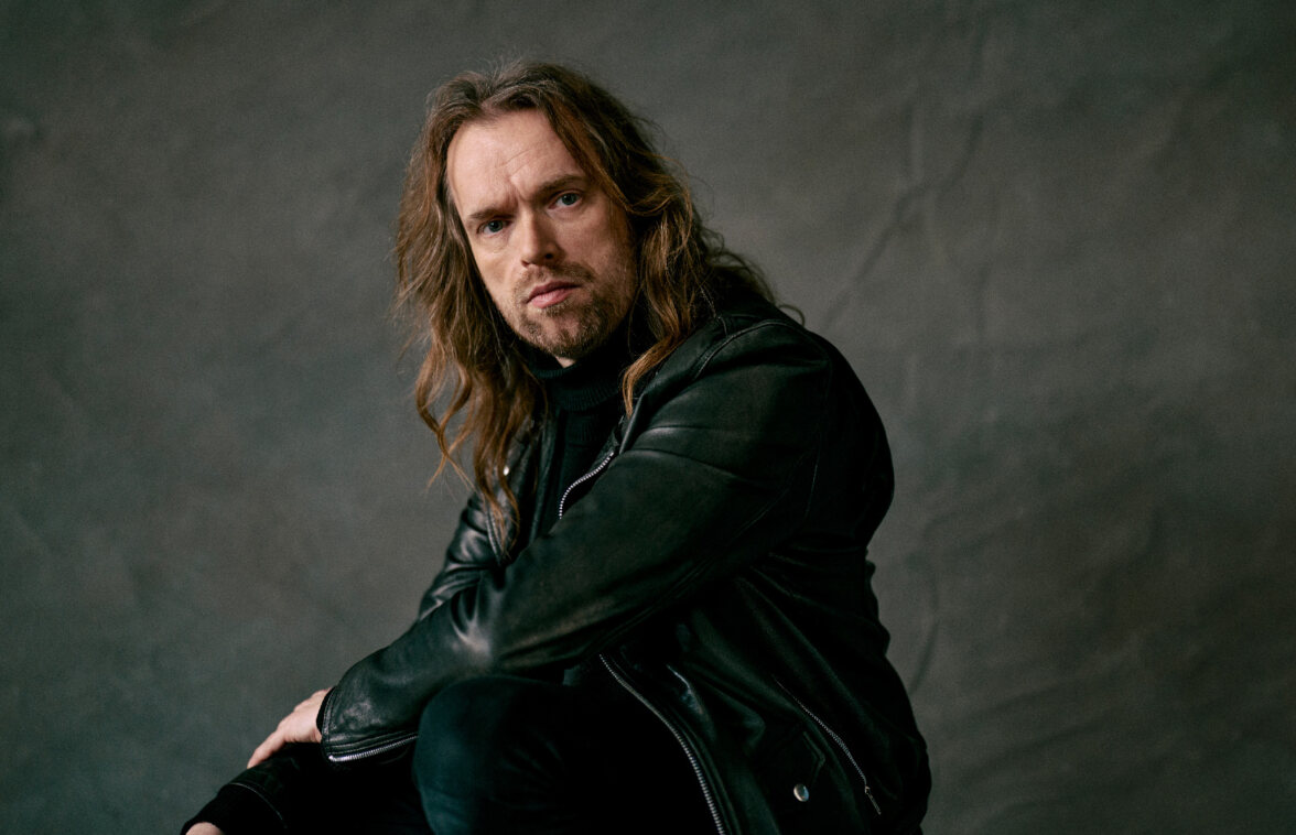 Anssi Kela valokuvastudiossa nahkatakissa ja mustissa farkuissa